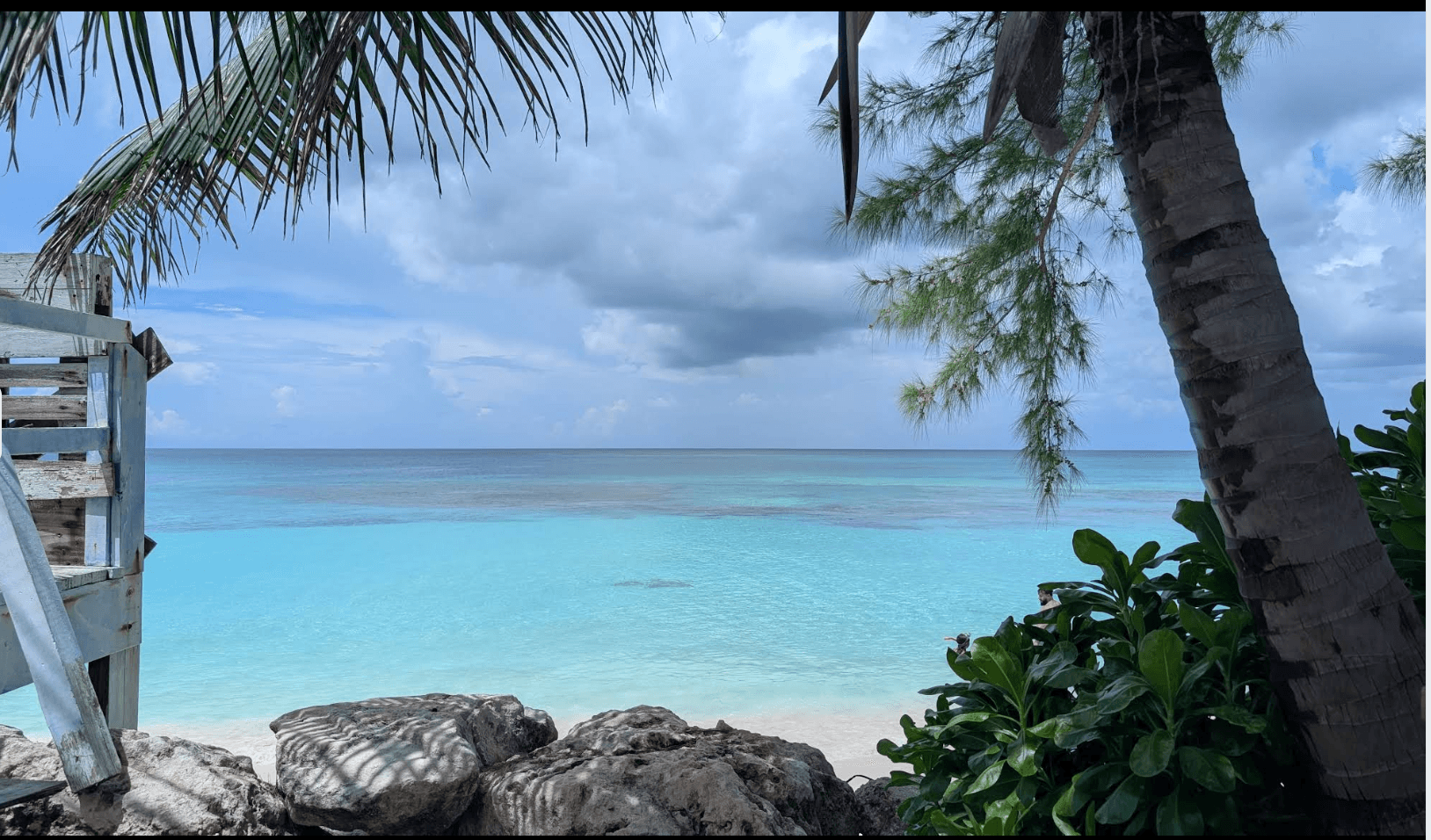 Turquoise water at Love Beach framed by palms and shoreline rocks