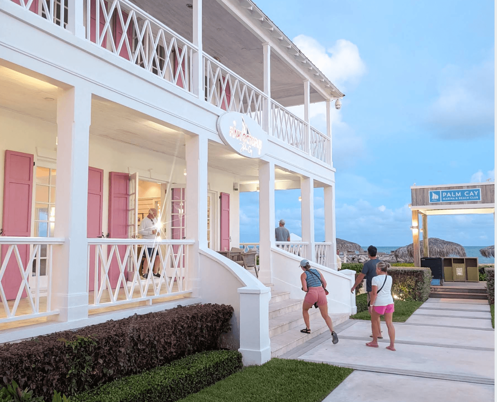 Pink Octopus restaurant with pink shutters beside the Palm Cay Marina and Beach Club sign
