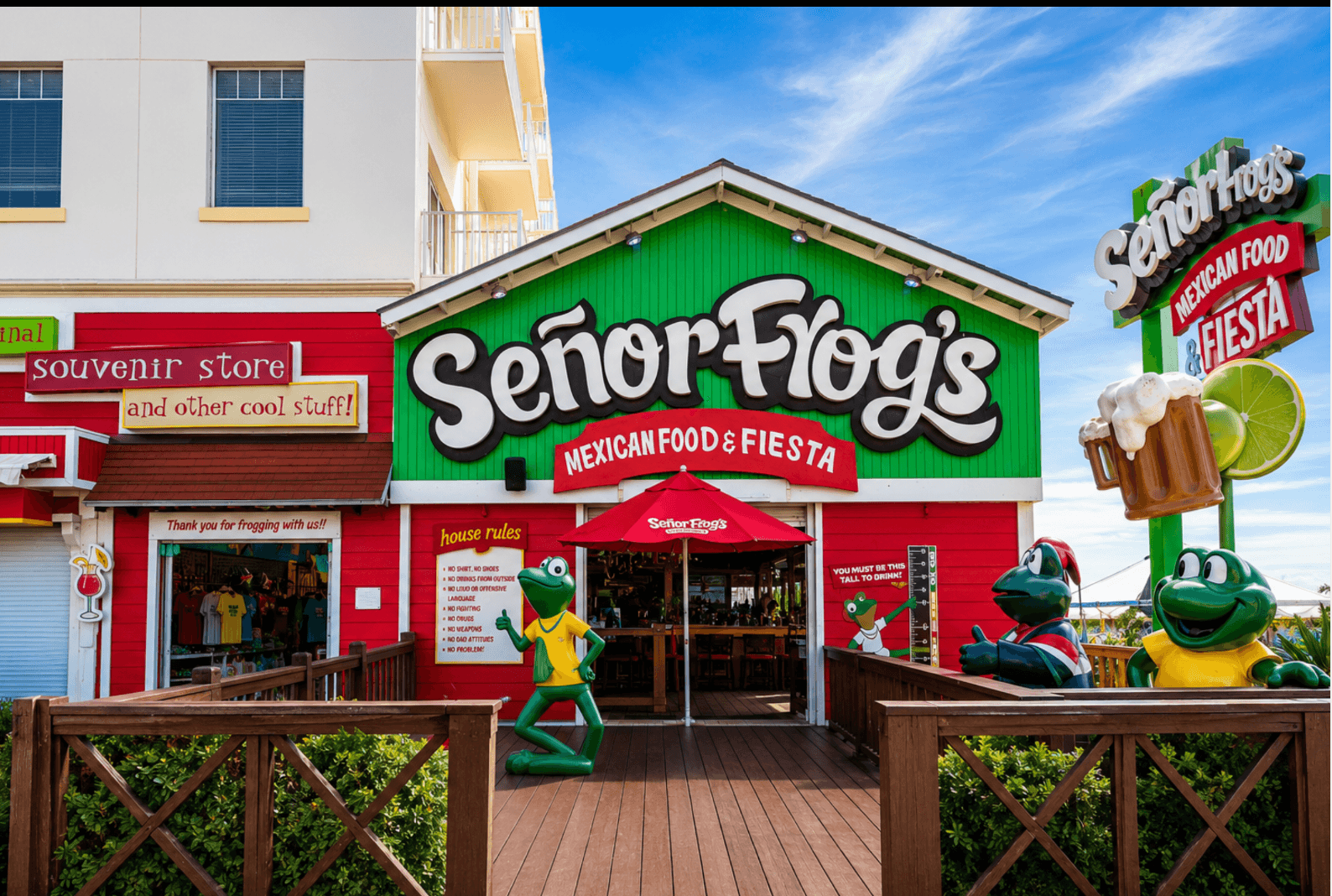 Red and green Señor Frog’s Nassau entrance with frog figures and a wooden walkway
